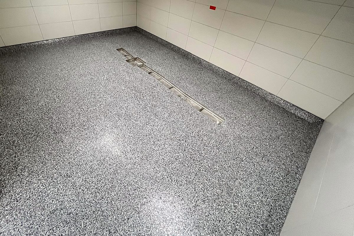 Detailansicht eines Sedimentbodens mit eingelassener Edelstahlrinne und Bodenablauf