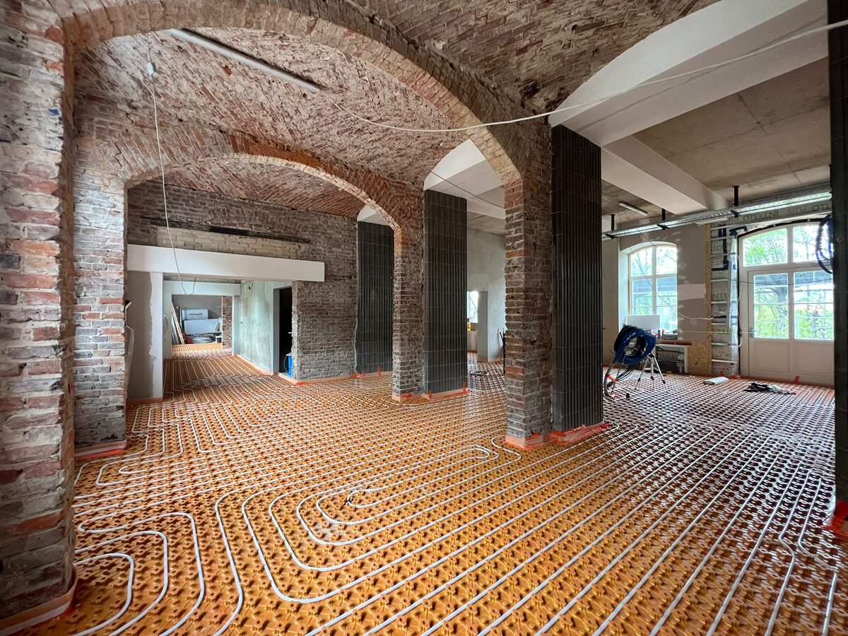 Großflächig verlegte Fußbodenheizung in einem historischen Gewölbekeller mit Backsteinmauerwerk