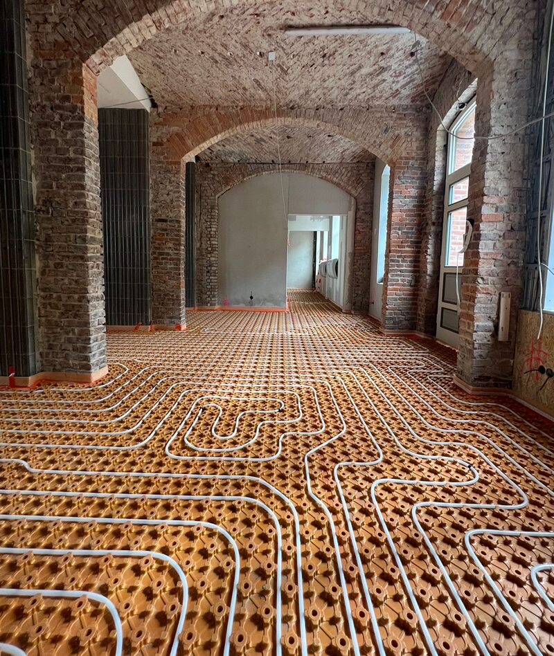 Schlüter-Verlegematte mit eingelegten Fußbodenheizungsrohren in einem Altbau-Korridor