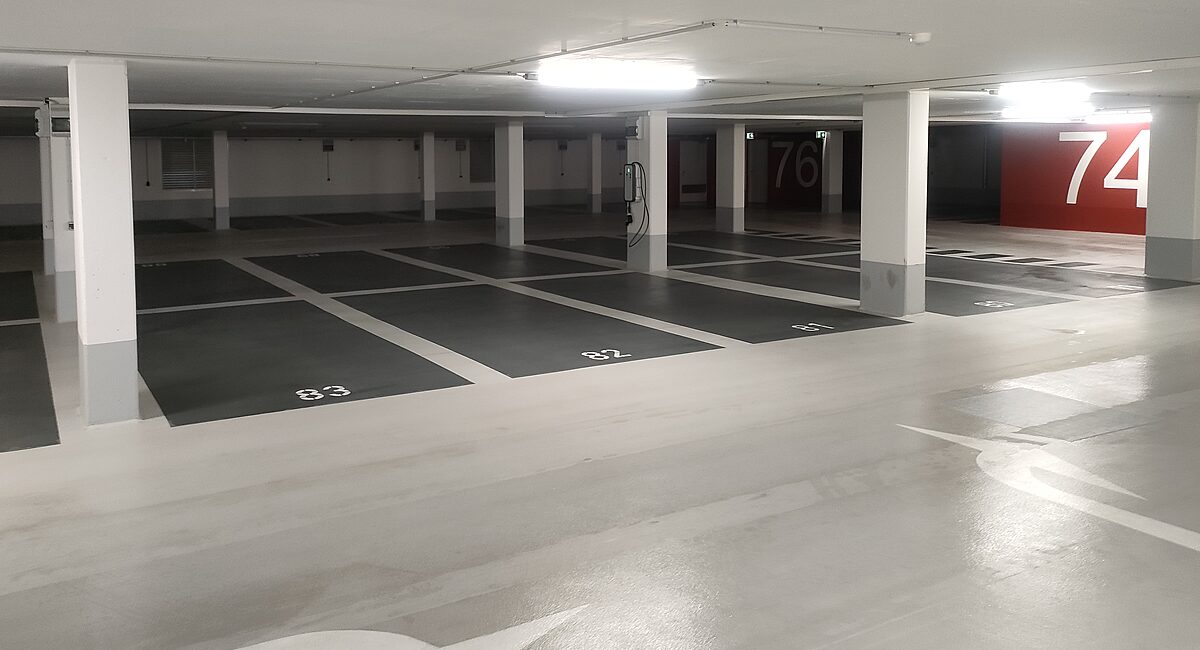 Tiefgarage mit OS-8-Beschichtung in Rot-Schwarz-Weiß – farbige Wandgestaltung mit rotem Fußgängerüberweg und nummerierten Stellplätzen 67 und 68