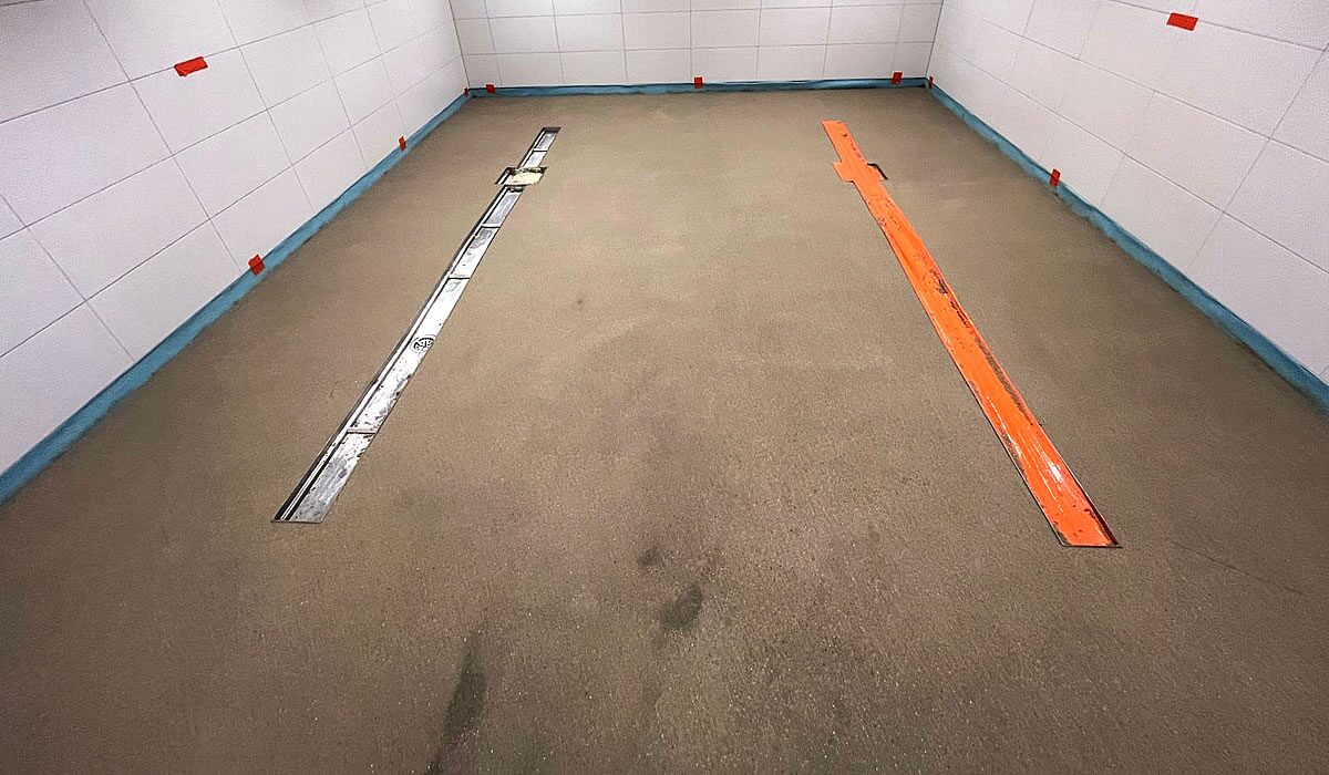 Frisch verlegter Industrieestrich mit zwei parallelen Edelstahl-Linienentwässerungen