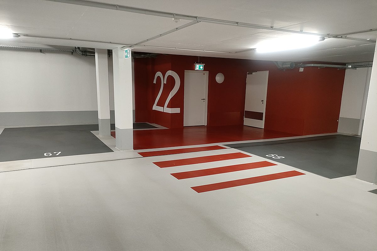 Übersicht Tiefgarage Hannover nach OS 8 Beschichtung – mehrere anthrazitfarbene Stellplätze mit weißen Stellplatznummern, hellgrauen Fahrgassen und weißen Säulen