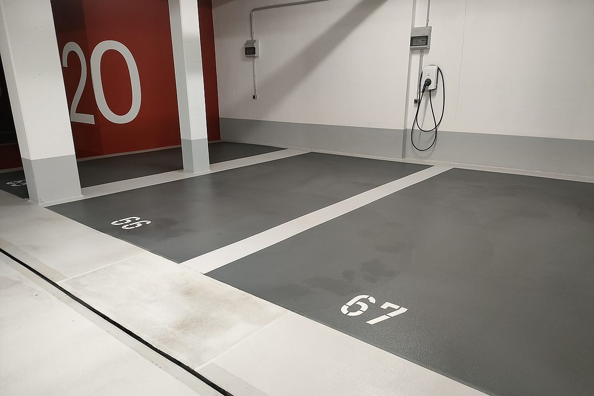 Tiefgarage Hannover – Aufzug-Bereich mit signalroter Wand, Etagennummer 2, hellgrauer Bodenfläche und mehreren Stellplätzen mit anthrazitfarbenen Markierungsfeldern