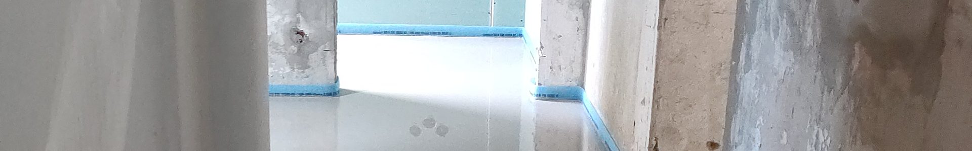 Calciumsulfat-Fließestrich – spiegelglatte Estrichoberfläche mit blauem Randdämmstreifen im Neubau