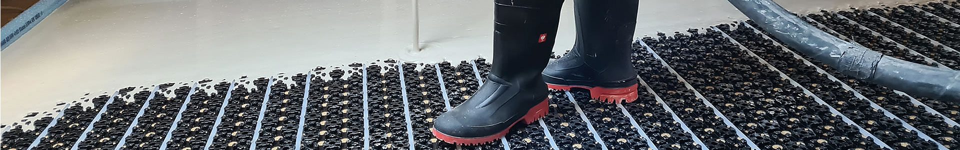 Estricharbeiten – Mitarbeiter beim Einbau von Zementestrich mit Glättemaschine in einem Rohbau
