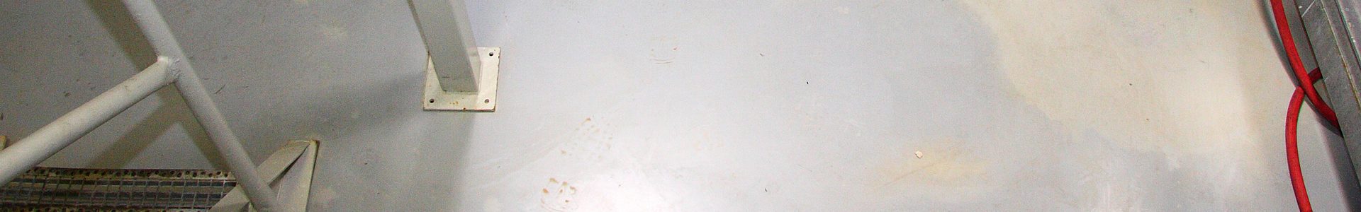 WHG-Beschichtung im Industrieboden – wassergefährdungsstoffgerechte Bodenbeschichtung mit Stahltreppengeländer und rotem Schlauch