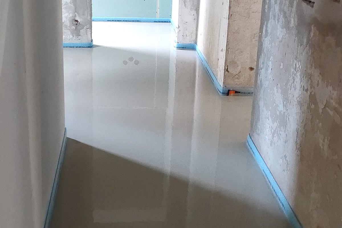 Calciumsulfat-Fließestrich – selbstnivellierender Anhydritestrich frisch verlegt in Altbau mit Randstreifen und spiegelglatter Oberfläches