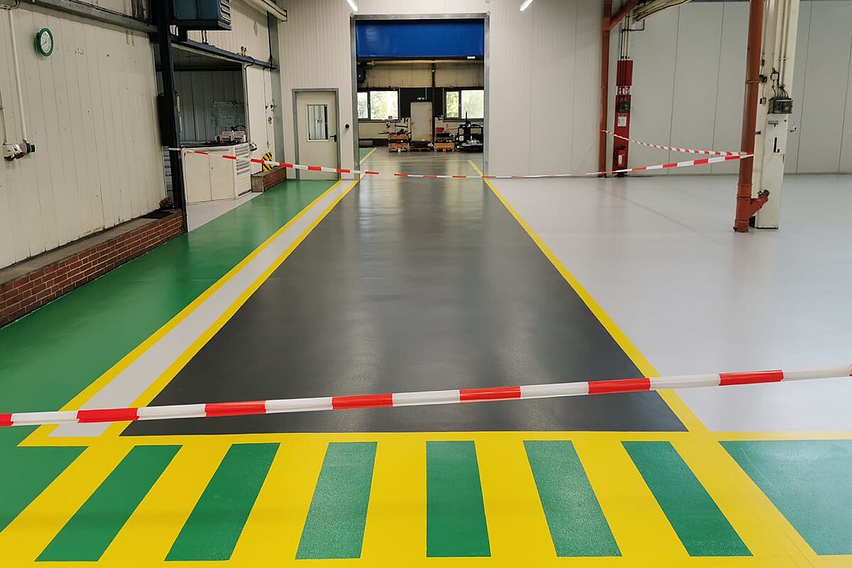 Großer Innenraum mit hochglänzender dekorativer Bodenbeschichtung in Hellgrau – spiegelnde Oberfläche reflektiert Deckenbeleuchtung